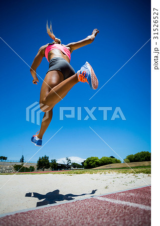 Female athlete performing a long jump Female athlete performing a long jump 31526527