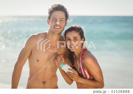 Young couple with sunscreen lotion on beach 31526888
