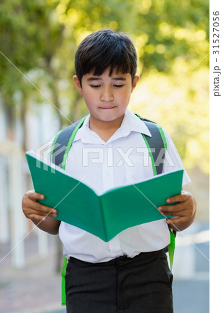 Happy schoolboy reading book in campus Happy schoolboy reading book in campus 31527056