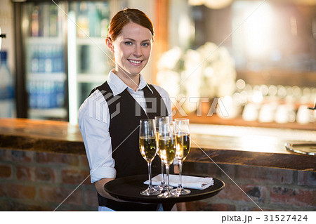 Portrait of waitress holding serving tray with champagne flutes Portrait of waitress holding serving tray with champagne flutes 31527424