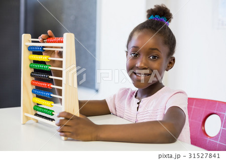 Schoolgirl using a maths abacus in classroom 31527841