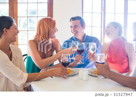 Friends holding wine glass while having meal 31527947