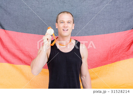 Athlete showing his gold medal in front of german flag Athlete showing his gold medal in front of german flag 31528214