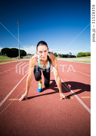 Portrait of female athlete in ready to run position 31528358