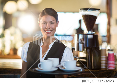 Portrait of waitress holding a tray with coffee cups Portrait of waitress holding a tray with coffee cups 31528423
