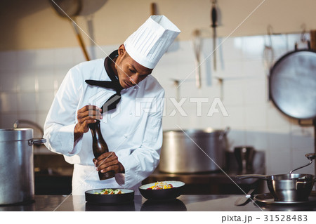 Chef sprinkling pepper on a meal 31528483