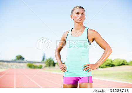 Tired female athlete standing on running track 31528718