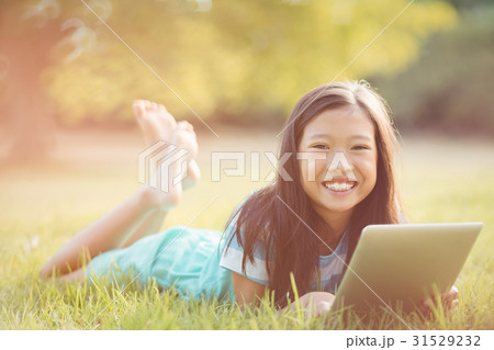 Portrait of smiling girl lying on grass and using digital tablet Portrait of smiling girl lying on grass and using digital tablet 31529232