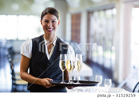 Portrait of waitress holding serving tray with champagne flutes Portrait of waitress holding serving tray with champagne flutes 31529259