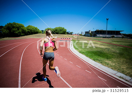 Rear view of female athlete running on the racing track 31529515