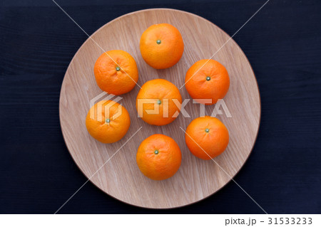黒バックの上の木製の皿に置かれた7個のミカン真俯瞰 31533233