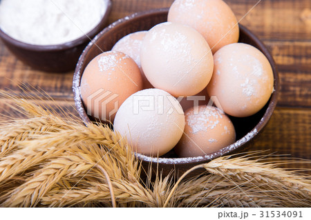 Fresh eggs in a brown bowl, wheat and flour on 31534091