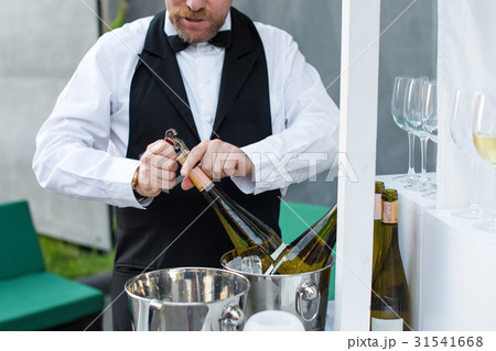 Professional waiter opening bottle of wine with 31541668