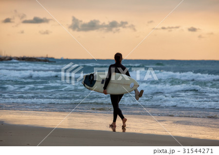 Sporty girl go to surfing. Woman in wetsuit and sunset or sunris Sporty girl go to surfing. Woman in wetsuit and sunset or sunris 31544271