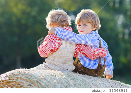 Two little kid boys, twins and siblings sitting on 31548911