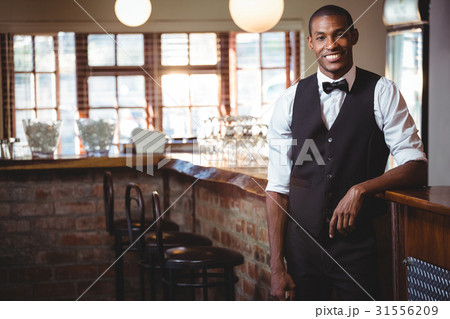 Portrait of bartender standing at bar counter 31556209