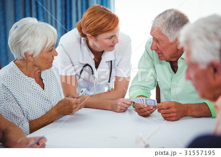 Smiling nurse looking at senior person during a game of cards 31557195