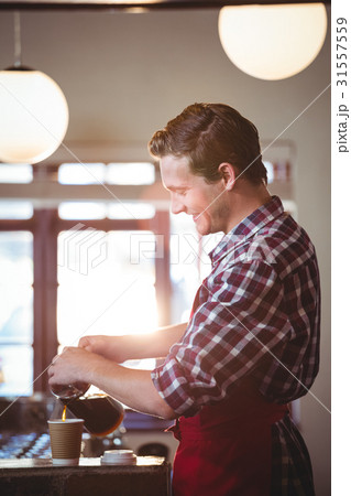 Smiling waiter pouring a cup of coffee Smiling waiter pouring a cup of coffee 31557559