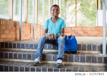 Smiling schoolboy sitting on staircase Smiling schoolboy sitting on staircase 31557603