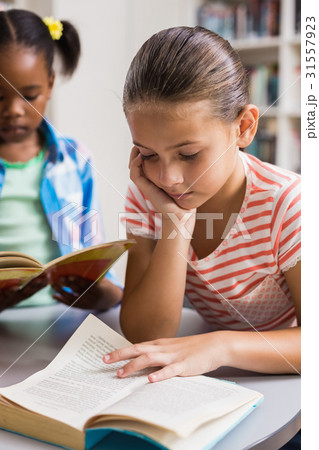 Schoolgirl reading a book in library 31557923