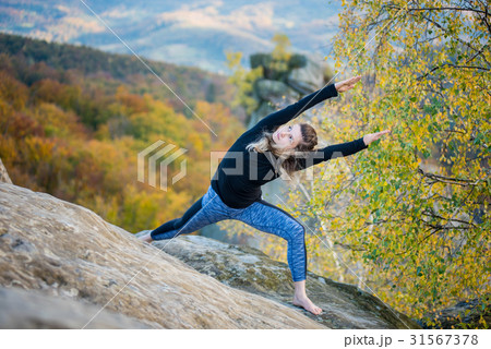 Woman is practicing yoga on the top of mountain 31567378