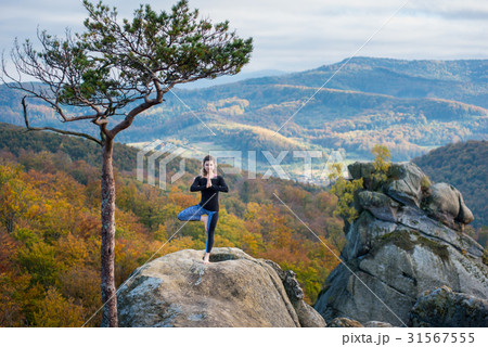 Woman is practicing yoga on the top of mountain 31567555