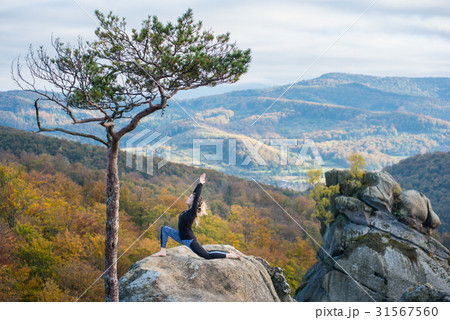 Woman is practicing yoga on the top of mountain 31567560