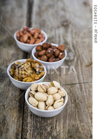 Four bowls with nuts on a  wooden table 31584503