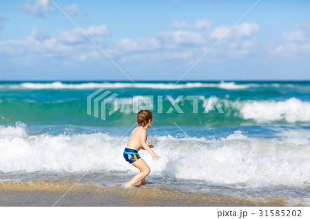 little blond kid boy having fun on ocean beach in 31585202