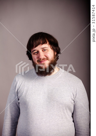 confident, lucky man with beard in front of grey 31587414