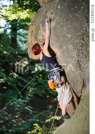 Female climber climbing with rope on a rocky wall 31589018