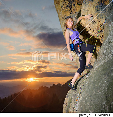 Female climber climbing with rope on a rocky wall Female climber climbing with rope on a rocky wall 31589093
