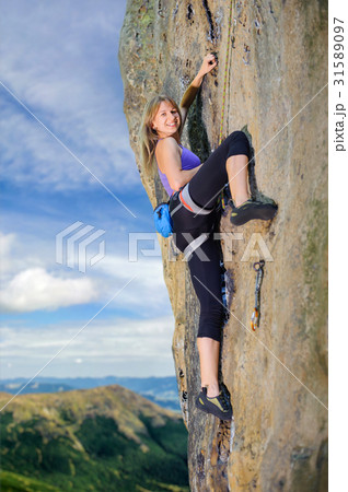 Female climber climbing with rope on a rocky wall Female climber climbing with rope on a rocky wall 31589097