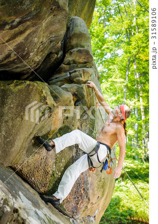 Male rock climber climbing with rope on rocky wall 31589106