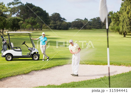 Male golfer playing on sand trap by woman 31594441