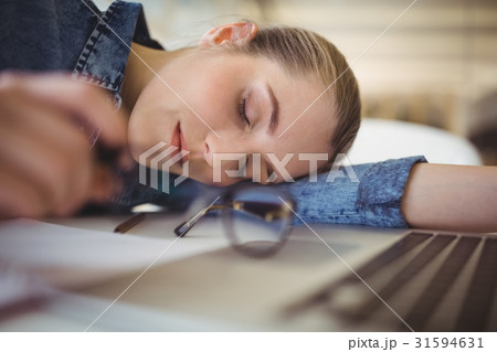 Tired businesswoman taking nap on desk in creative office 31594631