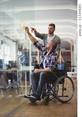 Handicap businessman with colleague sticking adhesive notes in office 31594685