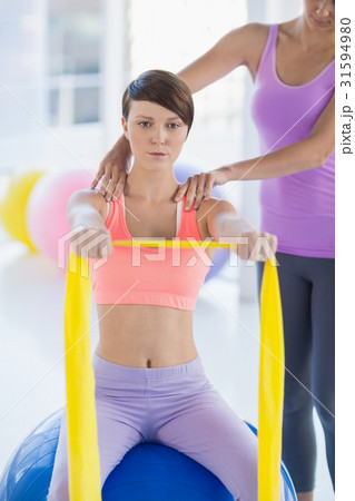 Young woman with trainer holding resistance band 31594980
