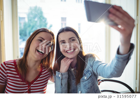 Cheerful female friends taking selfie at coffee shop Cheerful female friends taking selfie at coffee shop 31595077
