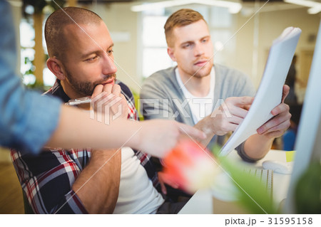 Businessman discussing documents with colleagues in office Businessman discussing documents with colleagues in office 31595158