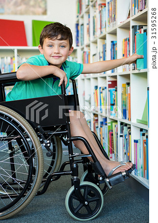 Elementary handicapped boy searching books in library Elementary handicapped boy searching books in library 31595268