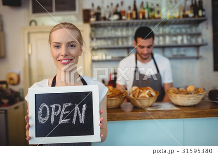 Portrait of confident waitress holding blackboard 31595380