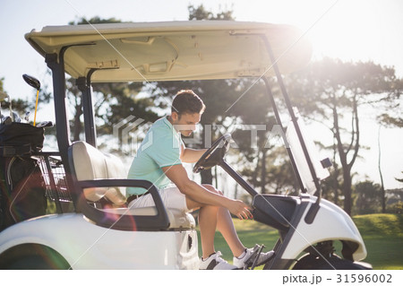 Side view of golfer man sitting in golf buggy 31596002