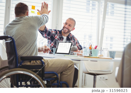 Handicap businessman giving high-five to colleague in office 31596025