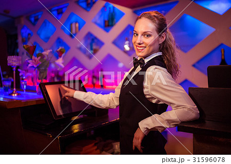Beautiful barmaid pointing at modern cash register 31596078