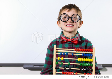 Cute boy with abacus against whiteboard in classroom 31596186