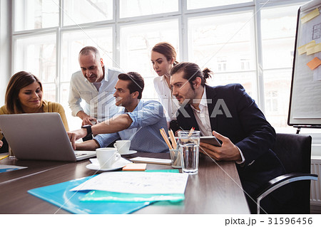 Businessman explaining colleagues with laptop in meeting room Businessman explaining colleagues with laptop in meeting room 31596456