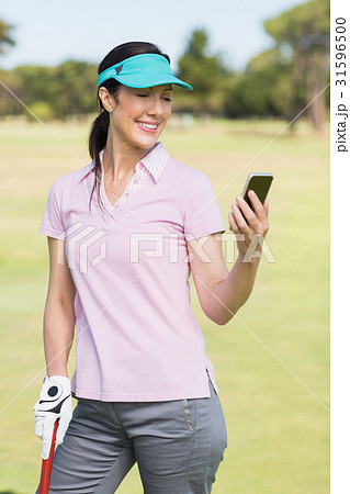Smiling golfer woman using phone 31596500