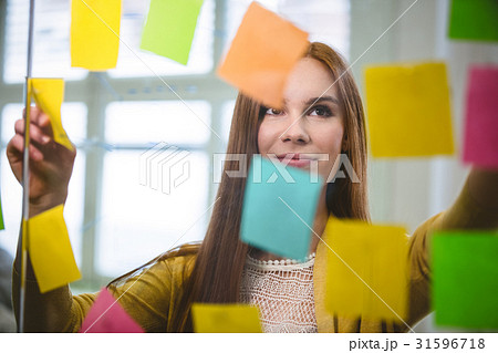 Businesswoman looking at sticky notes on glass Businesswoman looking at sticky notes on glass 31596718
