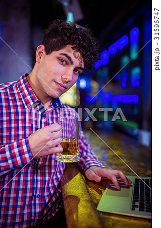 Portrait of man holding beer glass at bar counter 31596747